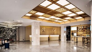 A modern hotel lobby with a high ceiling, a reception desk, and a bar area. - Hilton Garden Inn Chengdu Kuanzhai Alley (Chengdu)