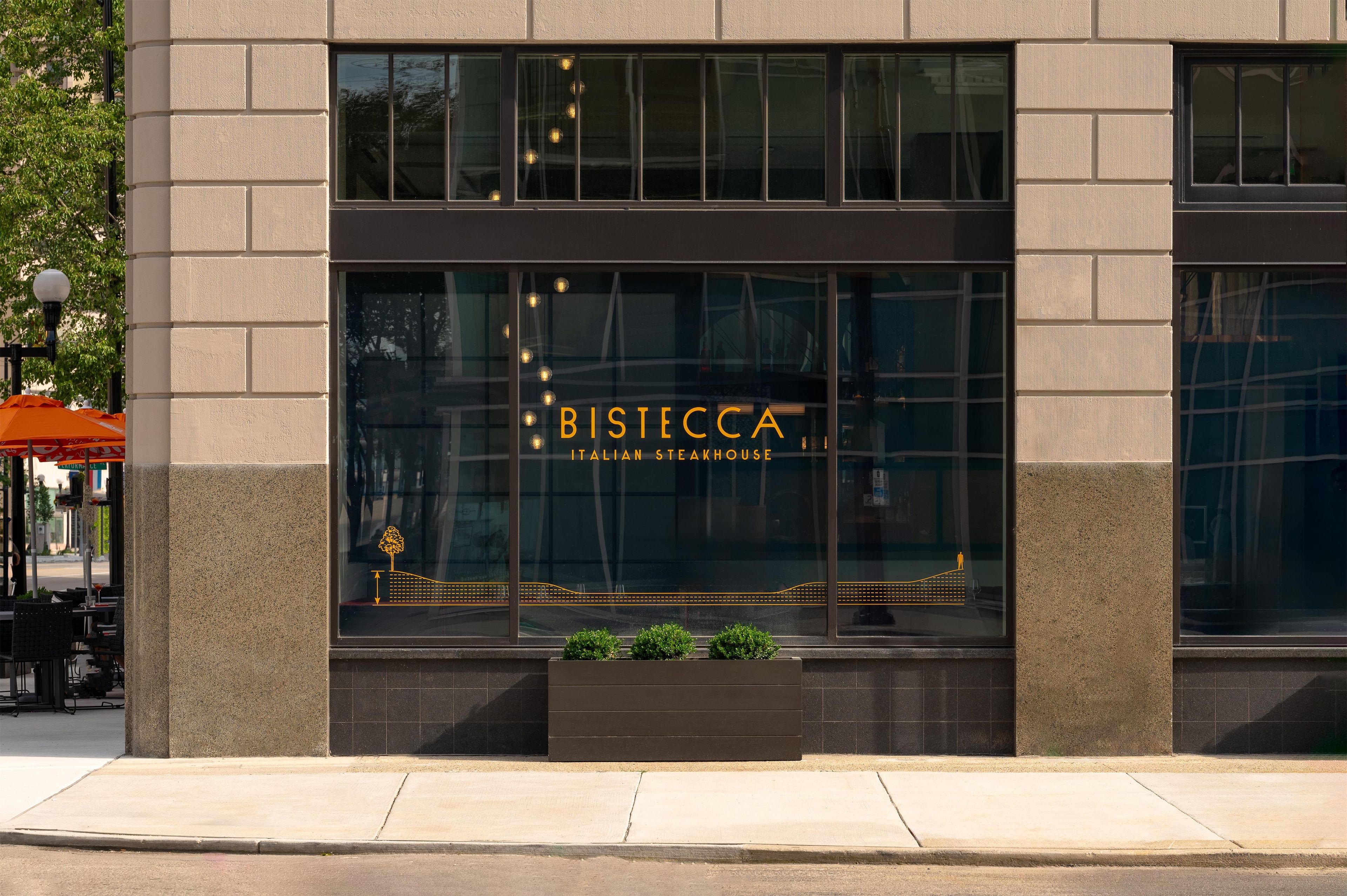 A building with a large window displaying the name 'BISTECCA ITALIAN STEAKHOUSE' and a decorative design.
