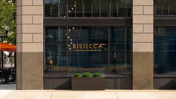 A building with a large window displaying the name 'BISTECCA ITALIAN STEAKHOUSE' and a decorative design.