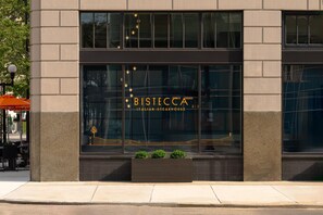 A building with a large window displaying the name 'BISTECCA ITALIAN STEAKHOUSE' and a decorative design. - Hotel Ardent Dayton Downtown, Tapestry Collection By Hilton (Dayton)