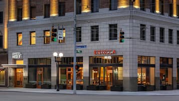 A corner building with a 'Hotel Ardent' sign, 'Bistecca' restaurant, and a 'One Way' street sign.