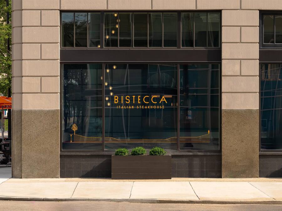 A building facade with the sign "BISIECCA ITALIAN STEAKHOUSE" and a small planter with greenery.