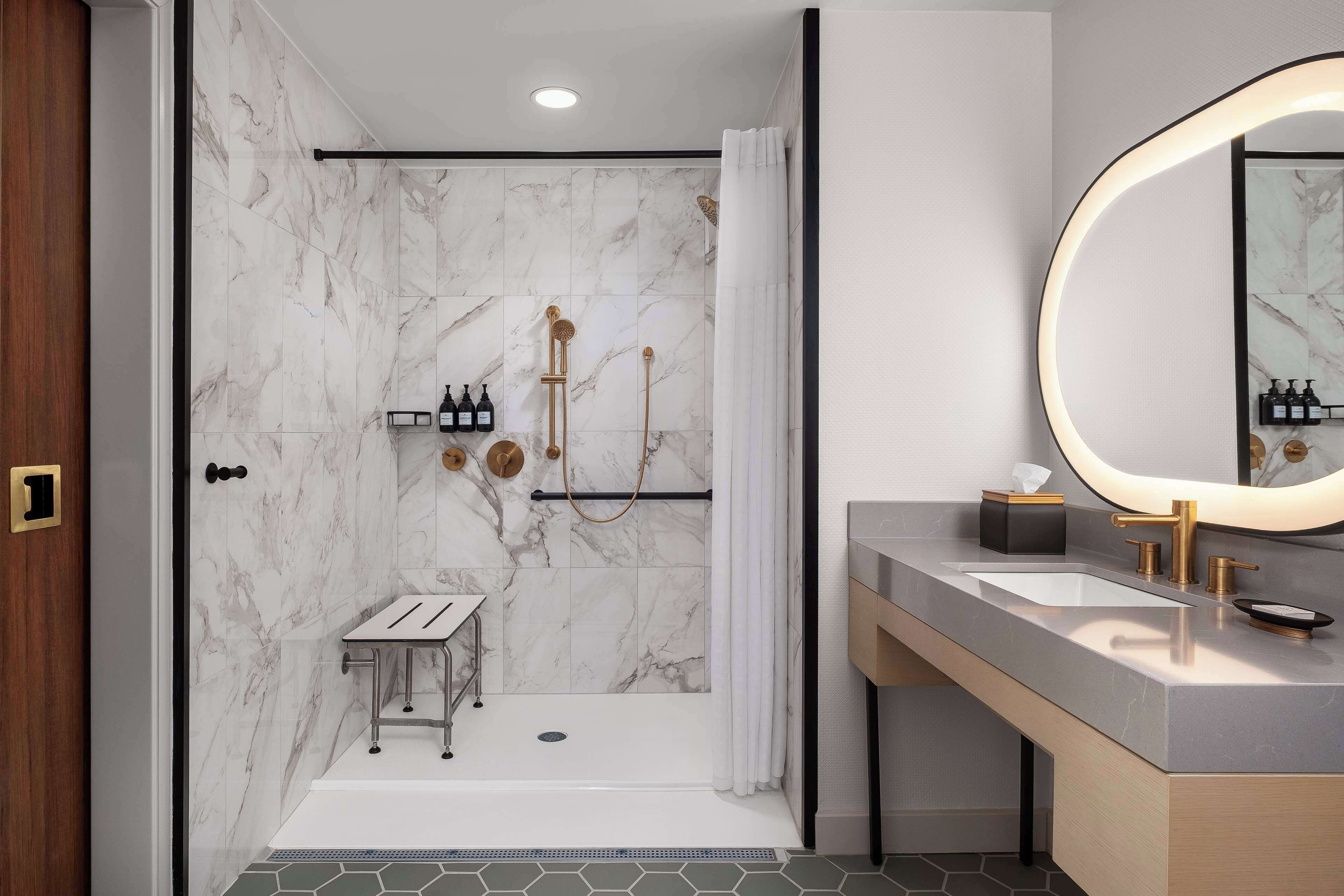 A modern bathroom with a shower, vanity, and a large mirror.