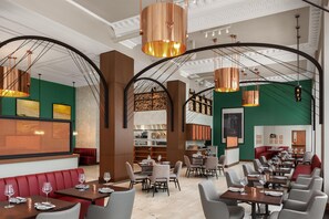 A restaurant with high ceilings, arched ceilings, and copper pendant lighting. Tables are set with wine glasses and cutlery. - Hotel Ardent Dayton Downtown, Tapestry Collection By Hilton (Dayton)