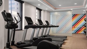 A row of treadmills in a gym with a colorful striped wall in the background.