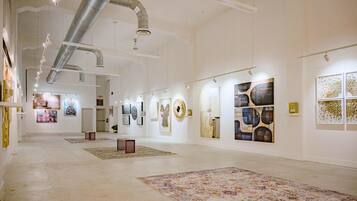An art gallery with white walls, artworks displayed on the walls, and a large, patterned rug on the floor.