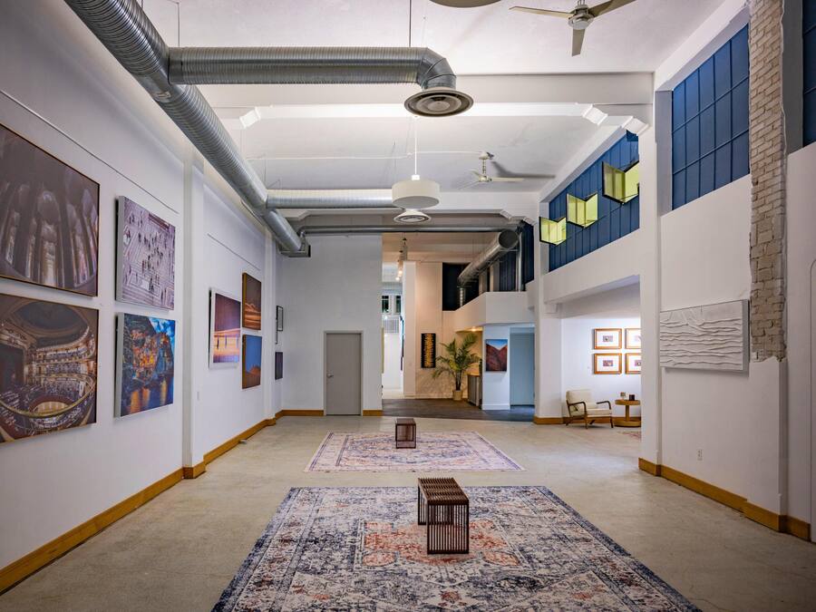 Un couloir orné de tableaux, avec un tapis à motifs et un banc.