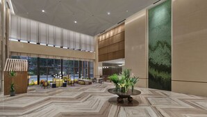 Un hall d’entrée spacieux, doté d’un haut plafond, de grandes fenêtres et d’une table ronde centrale agrémentée d’une composition florale.