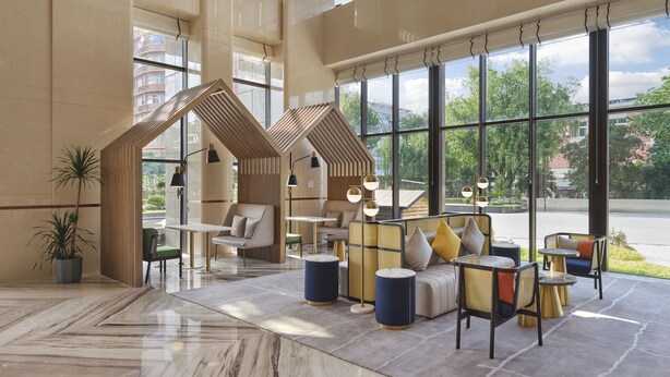 Un hall d’entrée spacieux avec de hauts plafonds, de grandes fenêtres donnant sur l’extérieur et un mobilier moderne.
