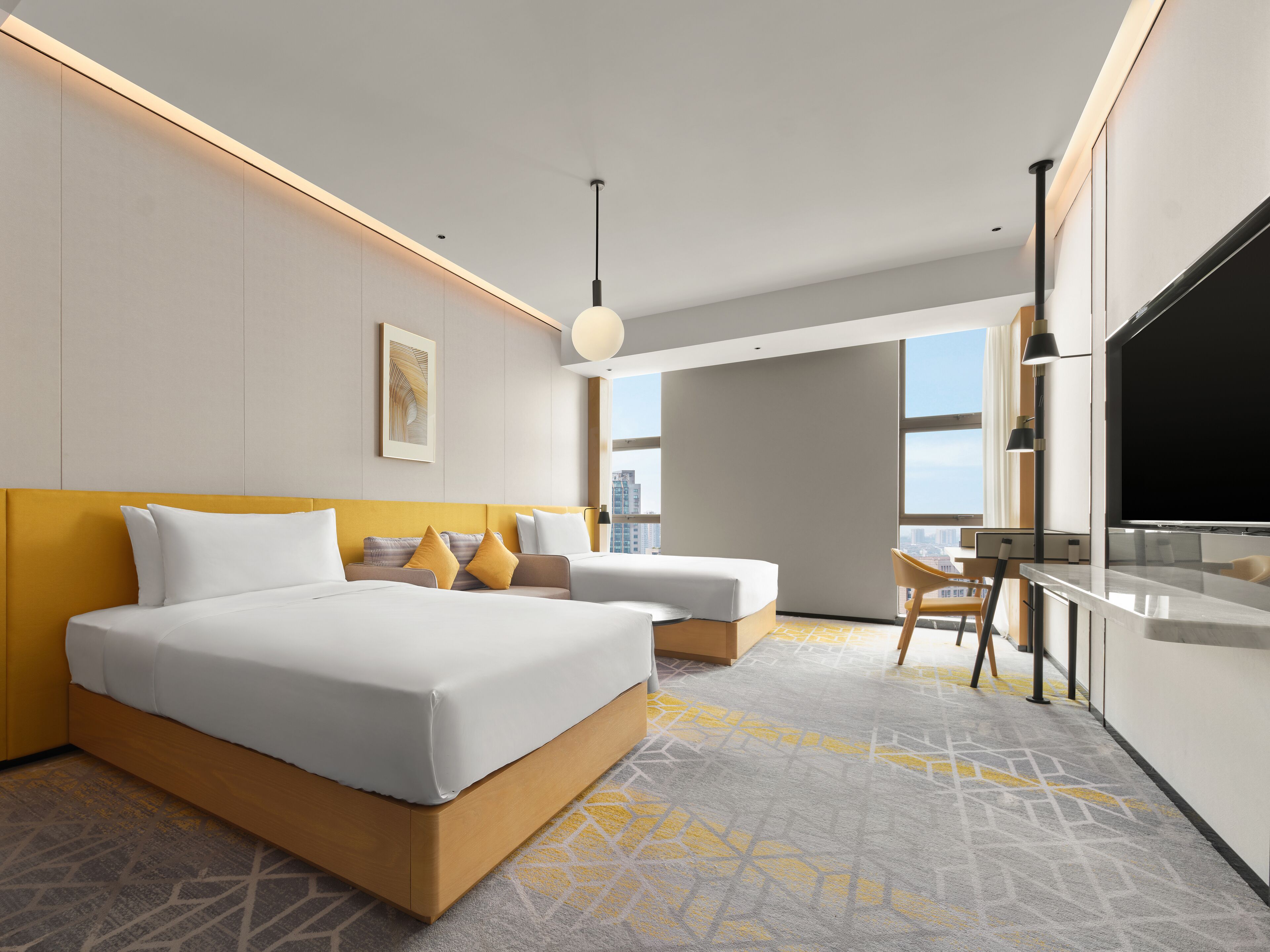 A modern hotel room with a large bed, a sofa, a desk, and a TV.