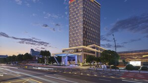 Un grand hôtel au design moderne, doté d’une entrée imposante et d’une grande enseigne lumineuse.