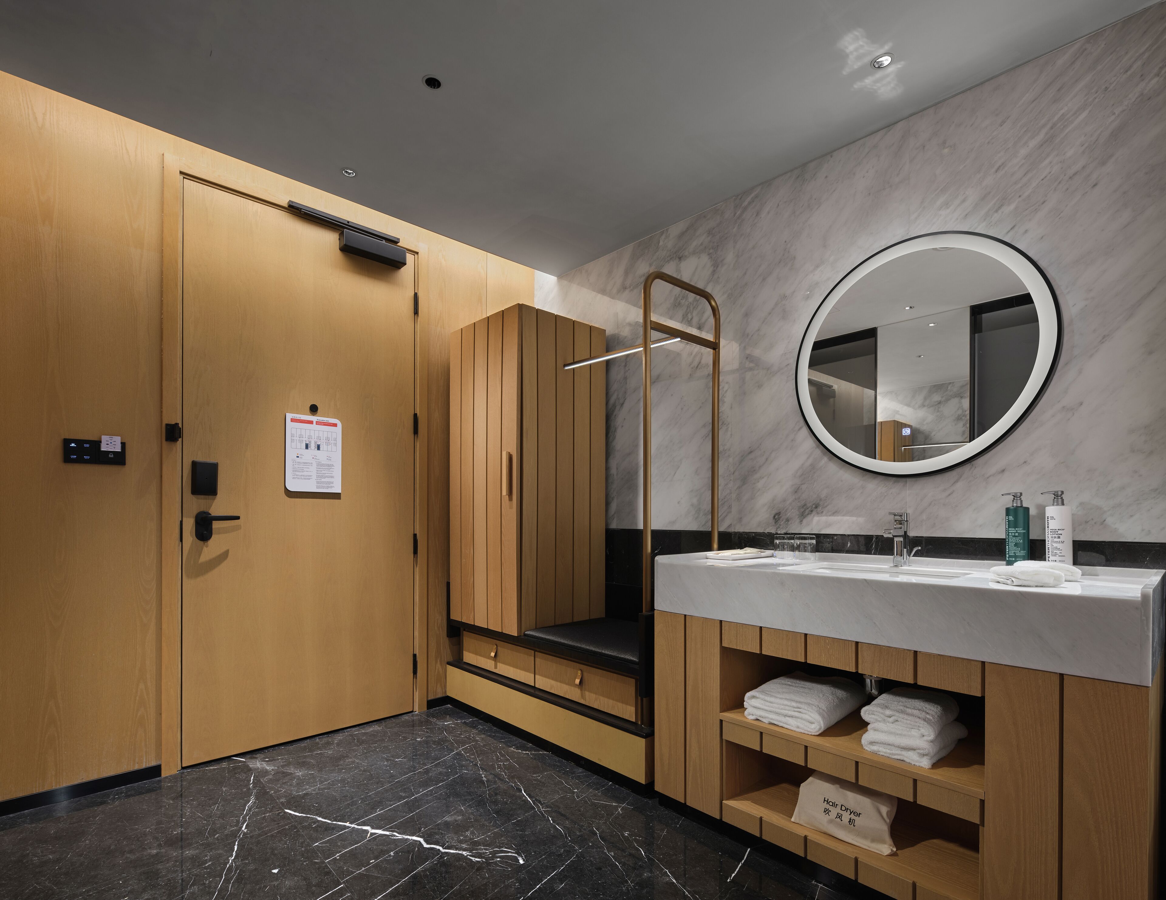 Une salle de bain moderne avec un meuble-lavabo en bois, un miroir rond et un sol en marbre.