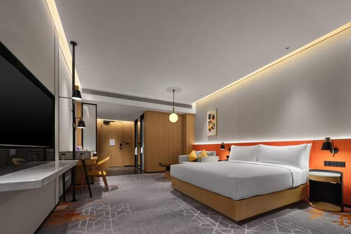 Ein modernes Hotelzimmer mit einem großen Bett, einem Schreibtisch, einem Stuhl und einem Fernseher.