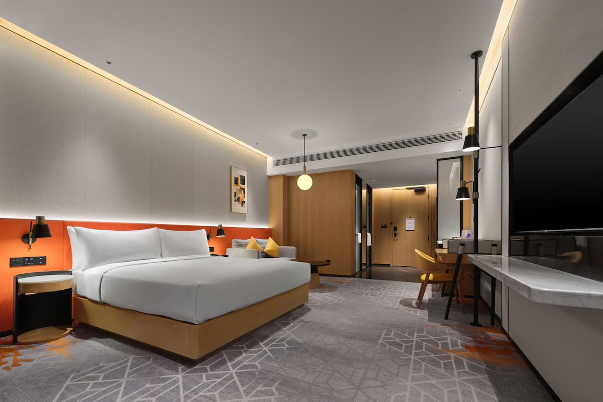 Ein modernes Hotelzimmer mit einem großen Bett, einem Nachttisch und einem Schreibtischbereich.