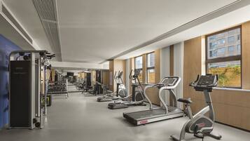 Un gimnasio moderno con cintas de correr, elípticas y máquinas de pesas.