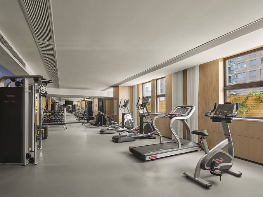 Un gimnasio moderno con cintas de correr, elípticas y máquinas de pesas.
