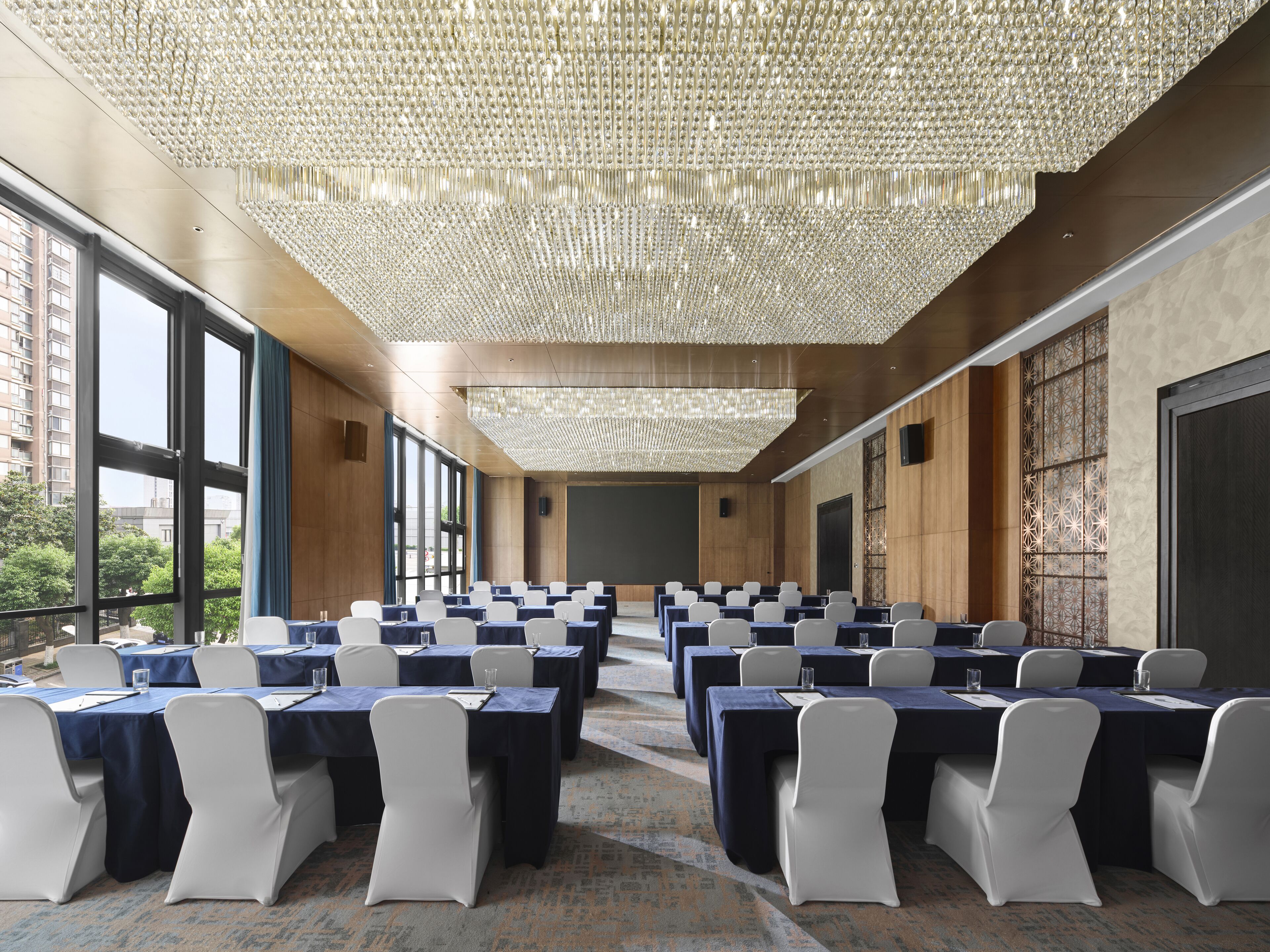 A conference room with rows of tables, large windows, and a decorative ceiling.