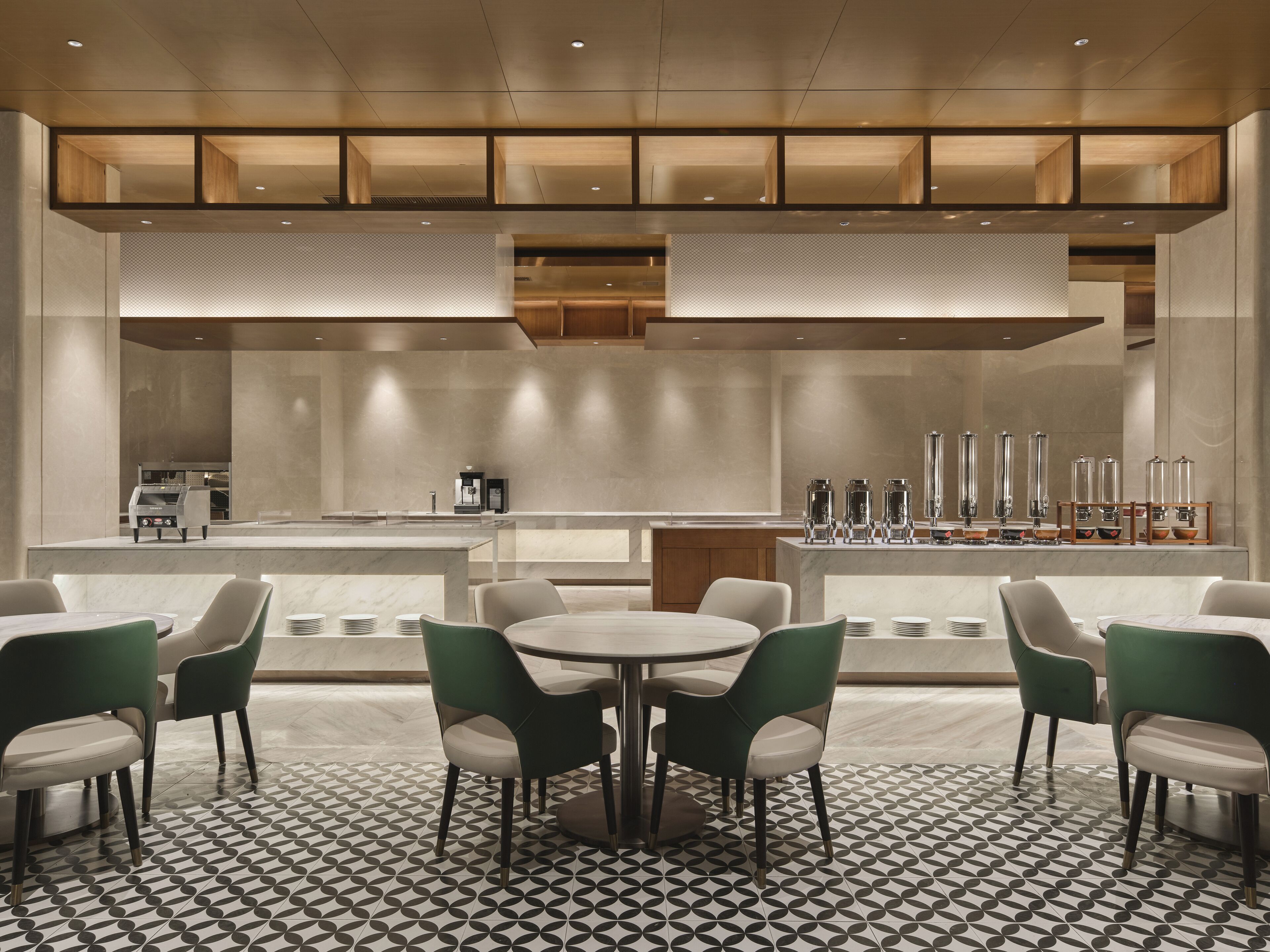 Een moderne eetruimte met een bar, groene stoelen en een patroon vloer.