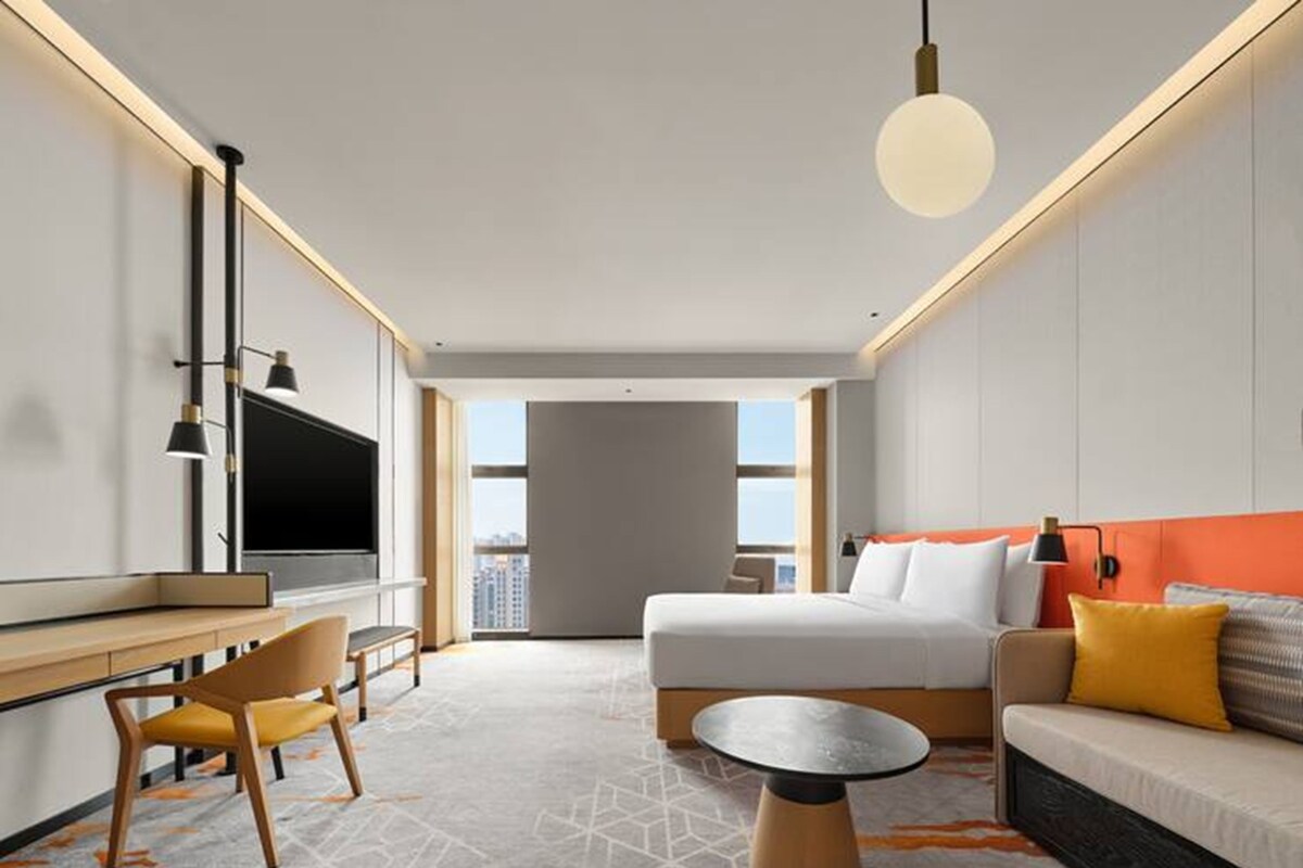 Une chambre d’hôtel équipée d’un lit, d’un bureau, d’une chaise, d’un canapé, d’une table ronde et d’un téléviseur.