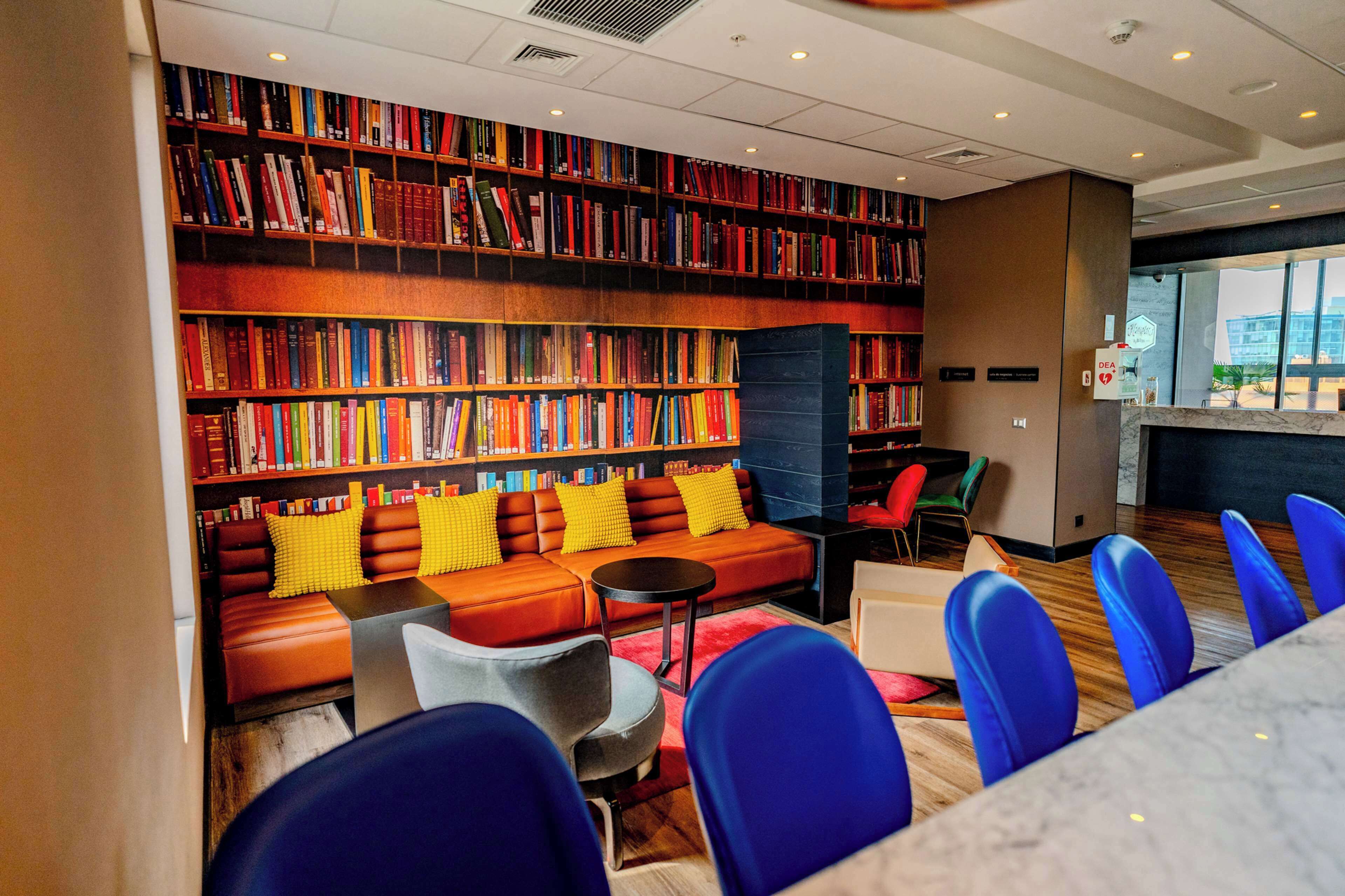 A library with bookshelves, a sofa, chairs, and a table.