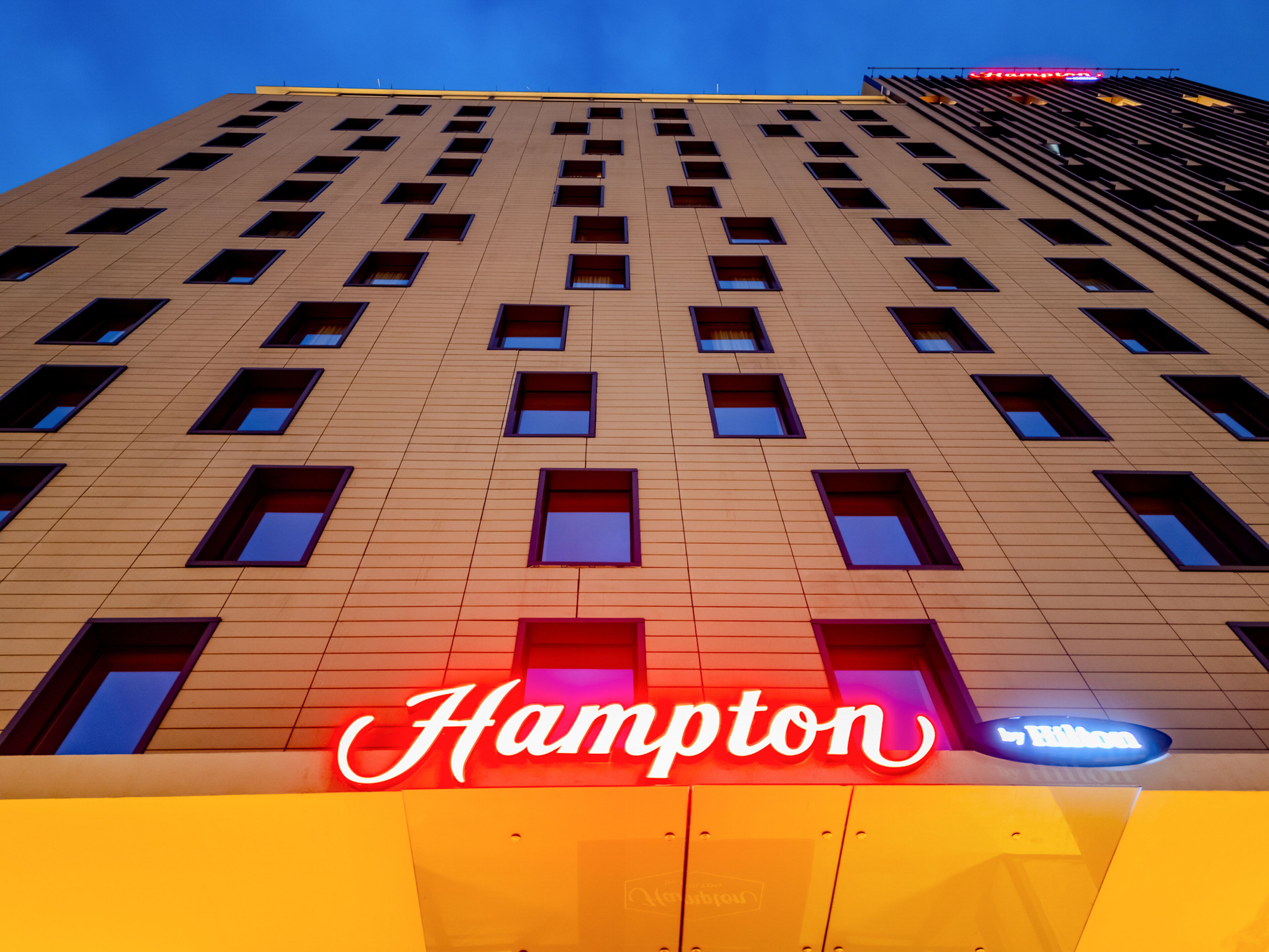 Un edificio de hotel con numerosas ventanas y un letrero llamativo de 'Hampton'.