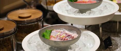 A buffet with various dishes served on ice, including a bowl of sliced meat and vegetables.