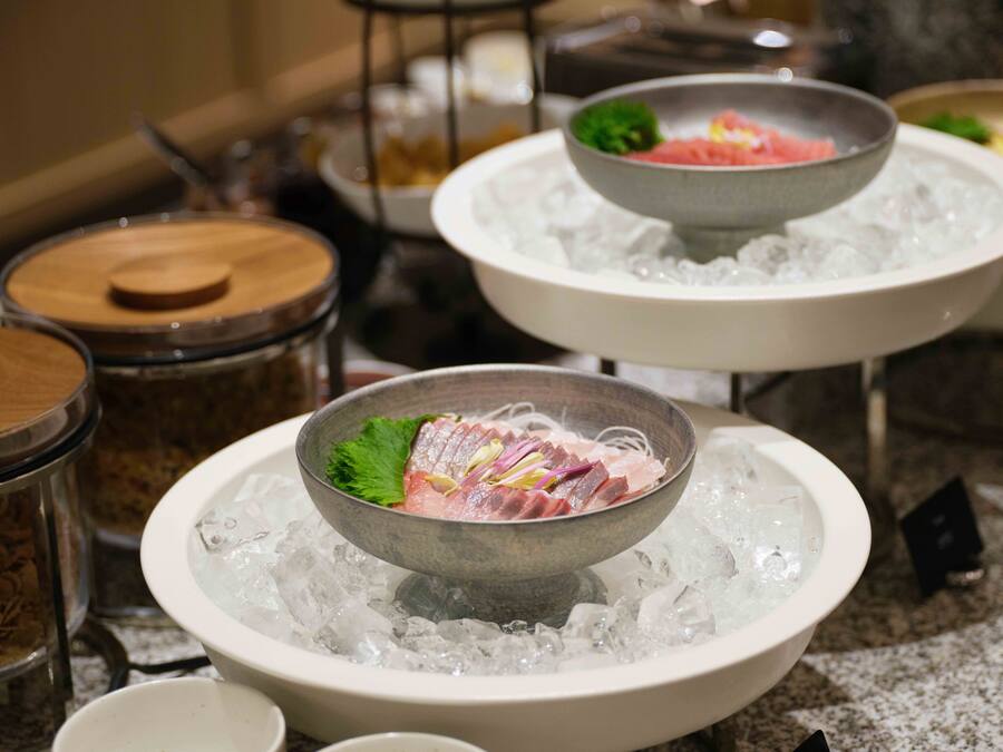A buffet with various dishes served on ice, including a bowl of sliced meat and vegetables.