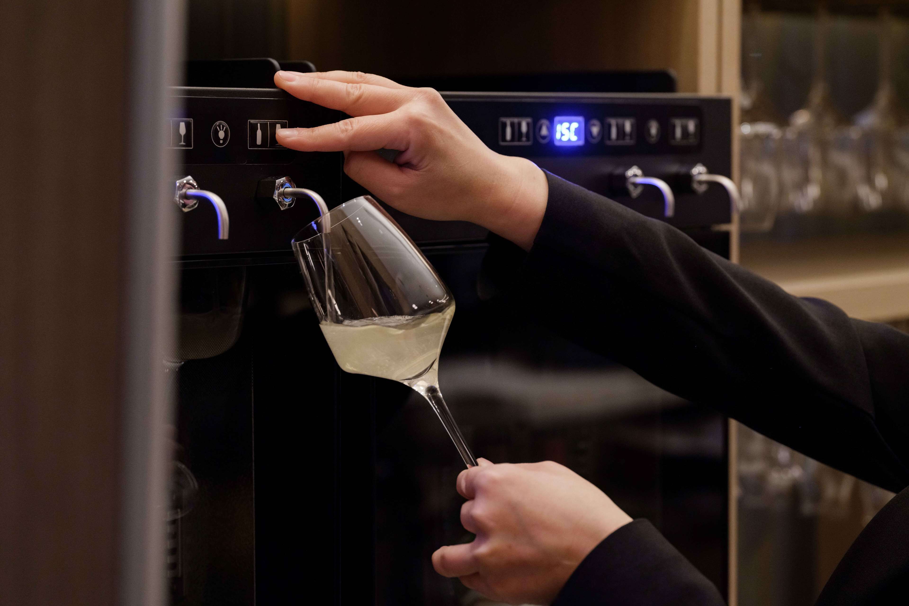 Una persona sirviendo vino con un dispensador y una copa.