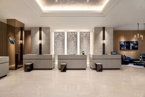 A hotel reception area with a modern design, featuring a central desk, seating area, and decorative wall panels. - DoubleTree by Hilton Toyama (Toyama)