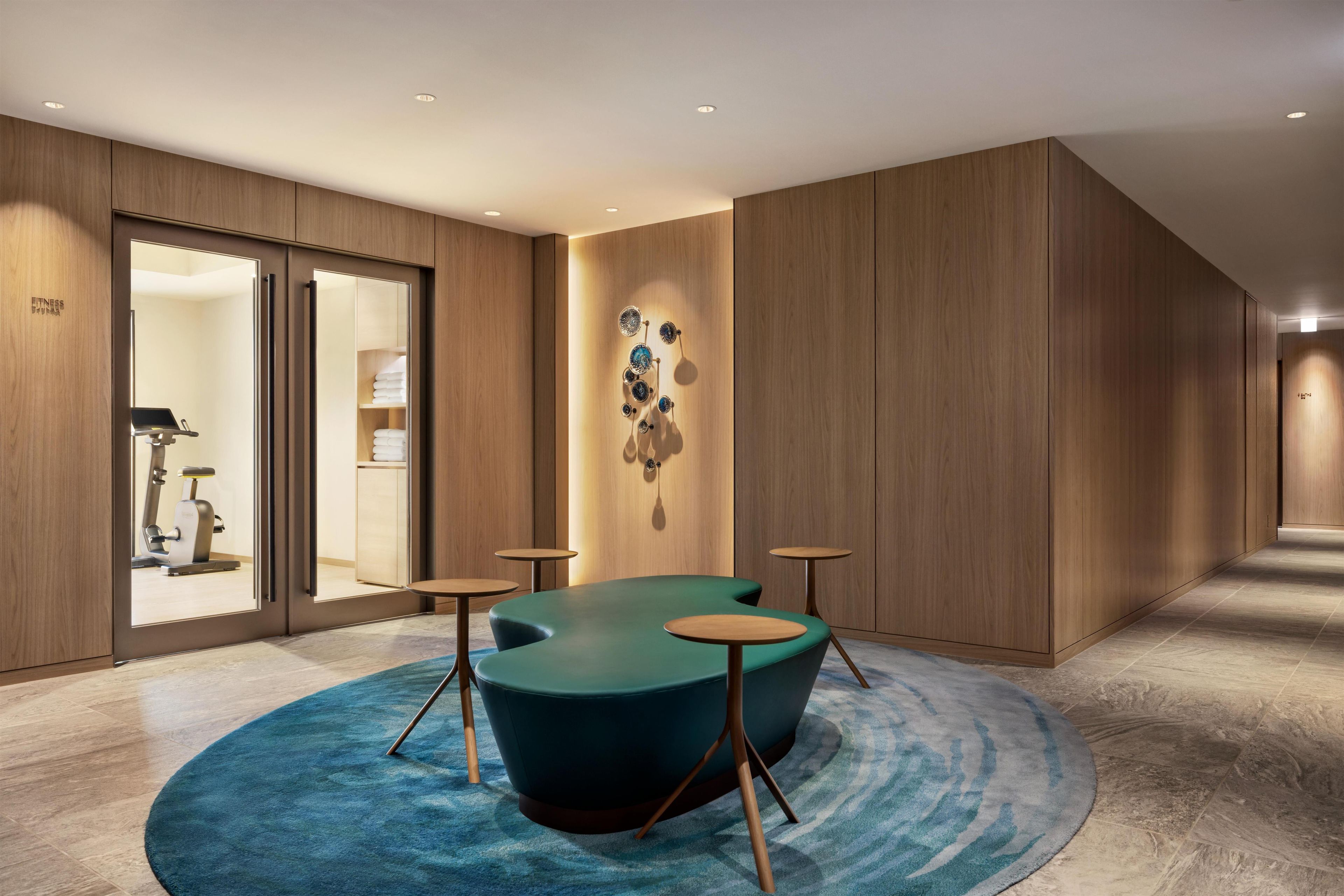 A modern hotel room with a large window, a blue carpet, and a wall-mounted decorative piece.