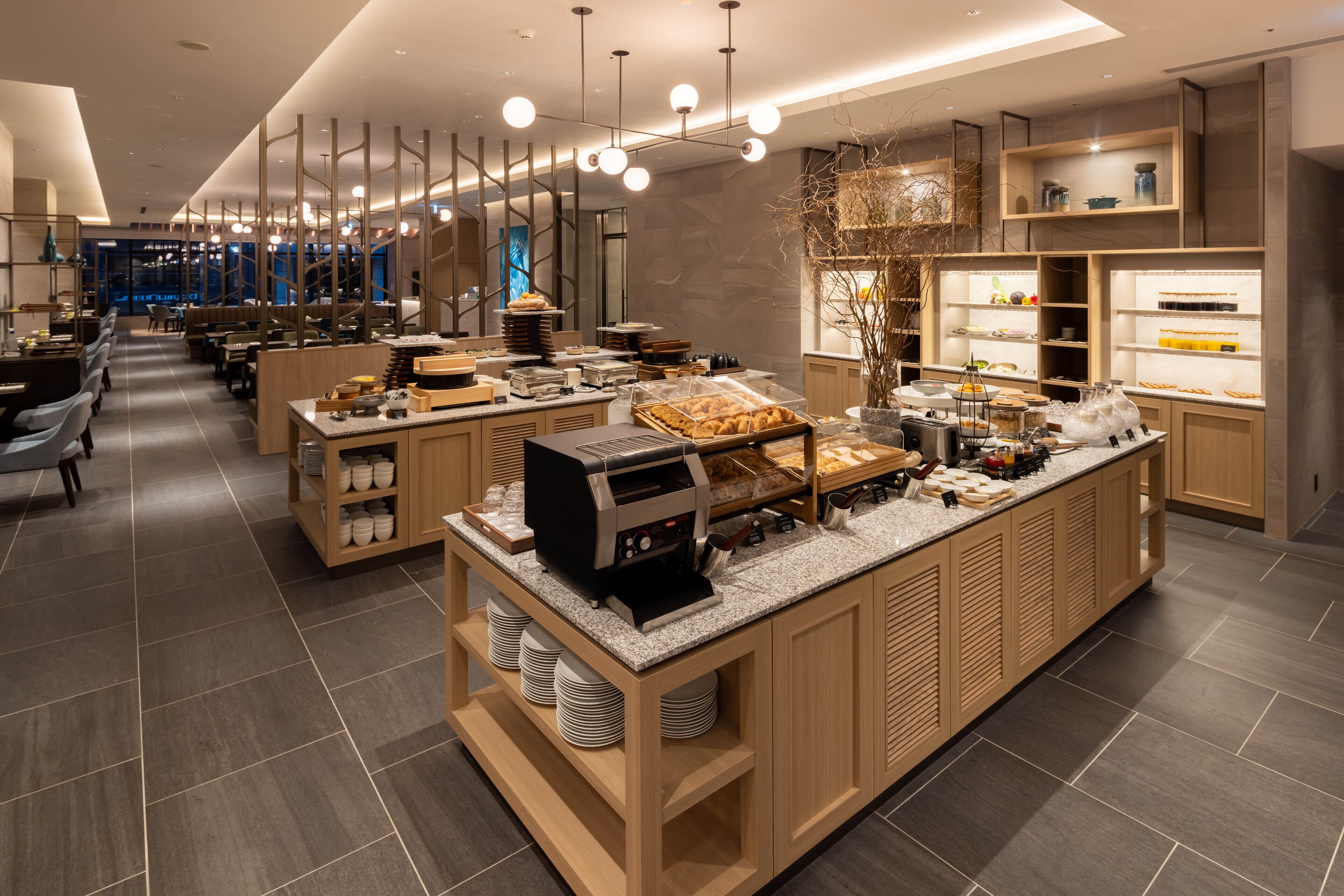 Uma área de café da manhã moderna com estação de serviço, assentos e vista para a paisagem urbana.