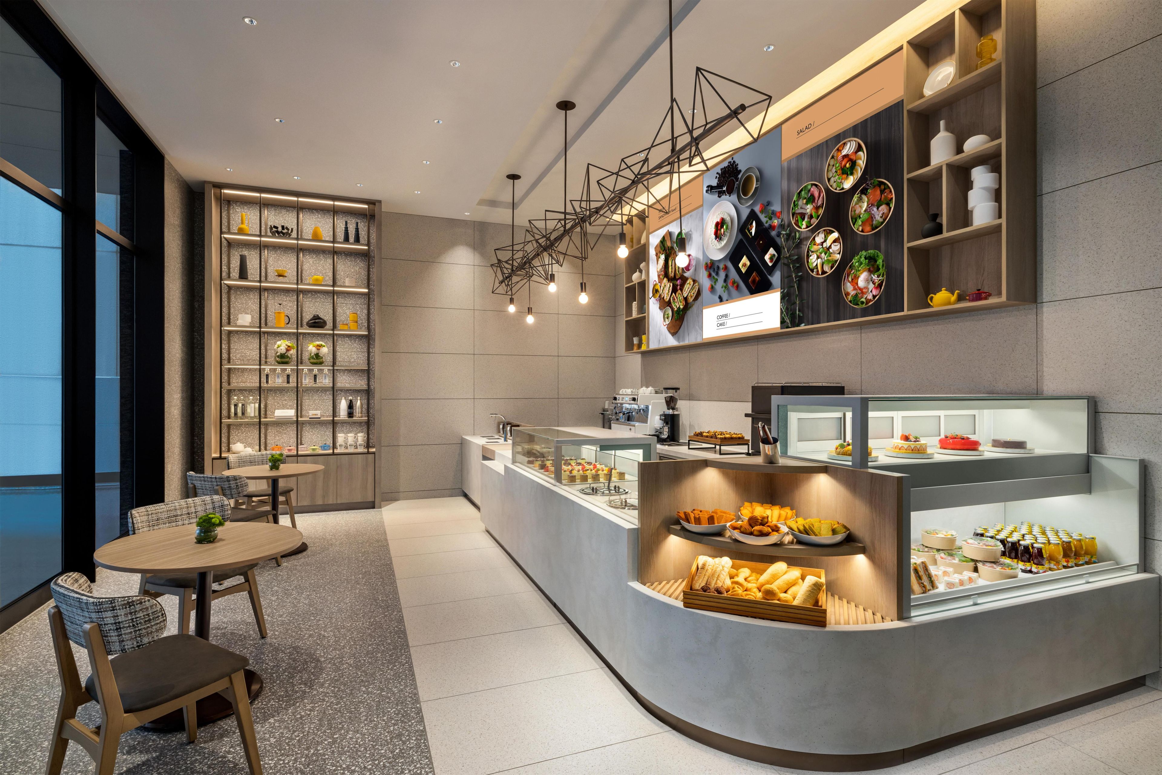 A modern cafe with a counter displaying pastries and a wall with food photography.