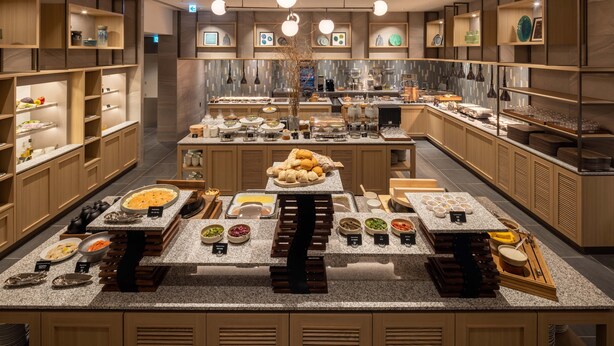 A modern kitchen with granite countertops, wooden cabinets, and various food items displayed on shelves and tables. - DoubleTree by Hilton Toyama (Toyama)