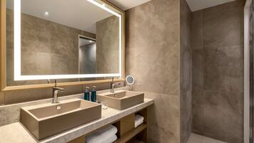 Un baño moderno con dos lavamanos, un espejo grande y una zona de ducha.