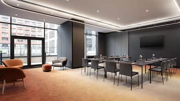 A modern conference room with a large table, chairs, and a TV screen.
