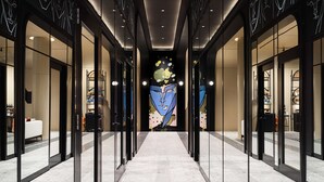 A modern hotel corridor with glass doors, a marble floor, and a central wall with a colorful mural. - Canopy By Hilton Toronto Yorkville (Toronto)