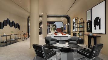 Een moderne hotellobby met een zithoek, een receptiebalie en een groot raam.
