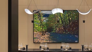 A modern dining area with a long table, multiple chairs, and pendant lighting.