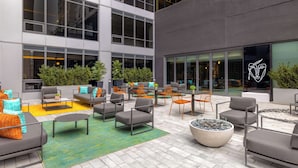 An outdoor seating area with multiple tables and chairs, surrounded by large windows and potted plants. - Canopy By Hilton Toronto Yorkville (Toronto)