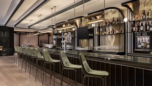 A modern bar area with a long counter, bar stools, and a wine display. - Canopy By Hilton Toronto Yorkville (Toronto)