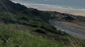 A coastal landscape with a beach, grassy hills, and a clear sky. - Immaculate 2-bed Lodge in Monreith (Newton Stewart)