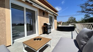 Eine Terrasse mit Tisch, Stühlen, einem Grill und einem Whirlpool.