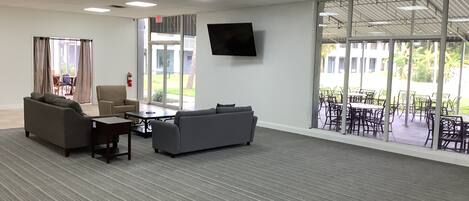 A spacious room with a grey carpet, two sofas, a coffee table, and a TV mounted on the wall.