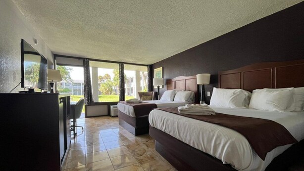 Quarto de hotel com cama grande, escrivaninha e vista para o exterior.
