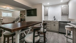 Een moderne keuken met een houten kookeiland, barstoelen en inbouwapparatuur.