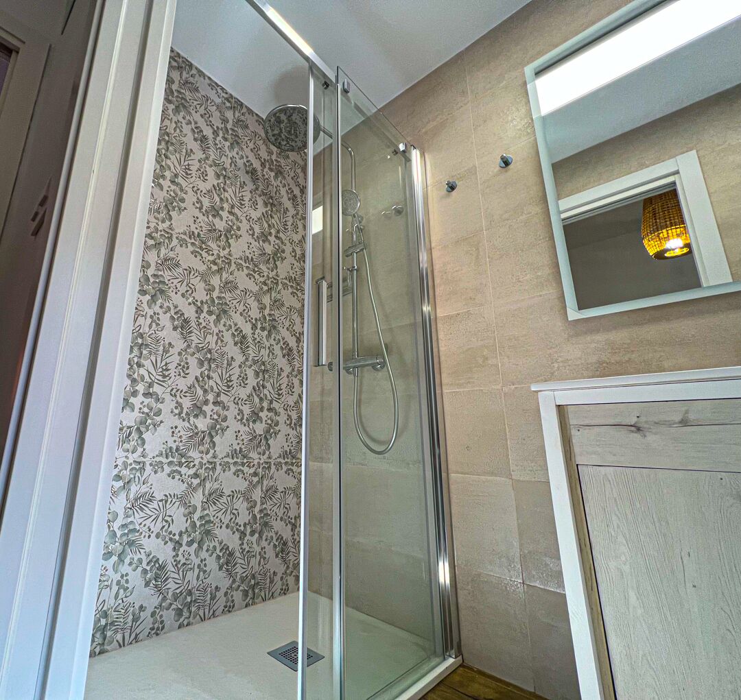A glass-enclosed shower with a showerhead and handheld shower attachment.