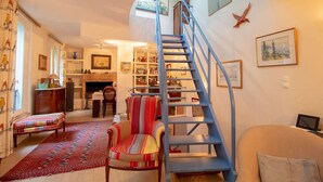 A cozy living room with a blue staircase, a fireplace, and a bookshelf. - Private House and Garden in Paris (Paris)