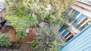 A courtyard with various plants and a wooden table. - Private House and Garden in Paris (Paris)