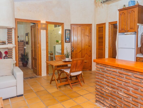 A compact kitchen with a wooden table and chairs, a white refrigerator, and wooden cabinets.