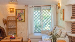 A cozy living room with a wooden table, a sofa, and a fireplace. - Cubo's Finca La Fuente del Pedregal Casa 3 / nature / community pool / free Wi-Fi (Coín)